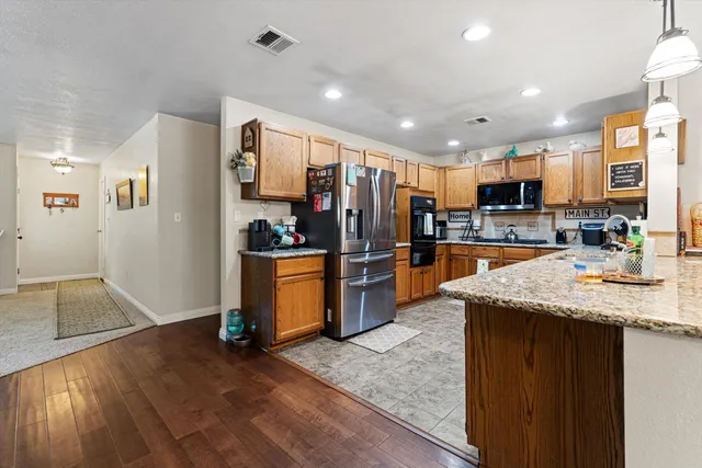 a kitchen with stainless steel appliances granite countertop sink refrigerator and cabinets