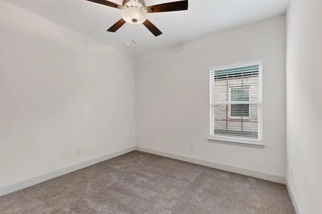 an empty room with a window and a fan