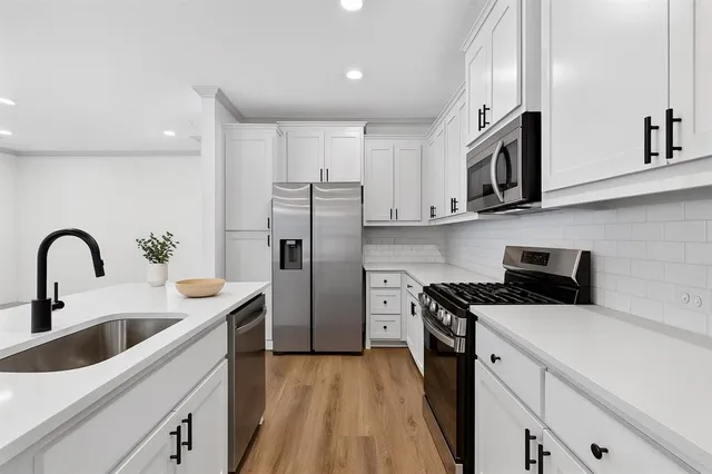 a kitchen with stainless steel appliances granite countertop a sink a stove a refrigerator and cabinets