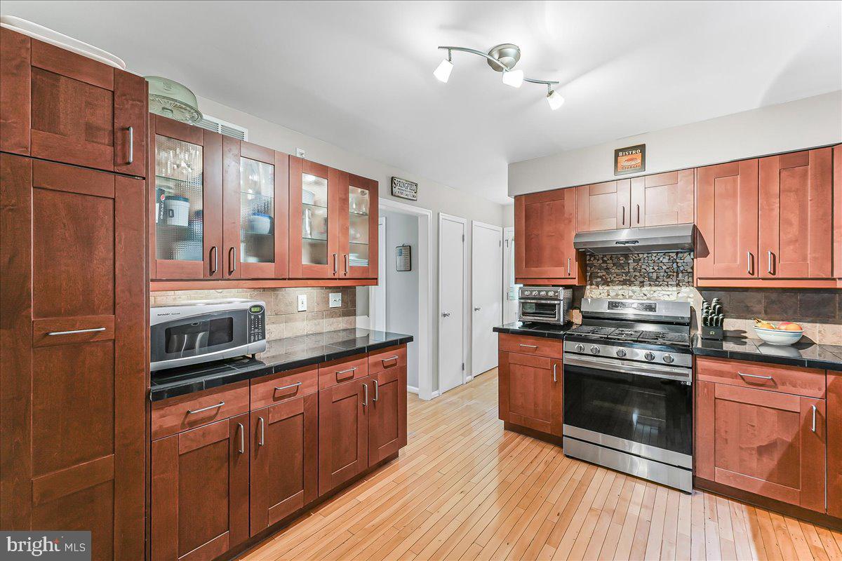 208 Rambling Way Springfield, PA 19064 - Photo 8 of 39 a kitchen with stainless steel appliances granite countertop wooden cabinets a stove top oven a sink and dishwasher with wooden floor