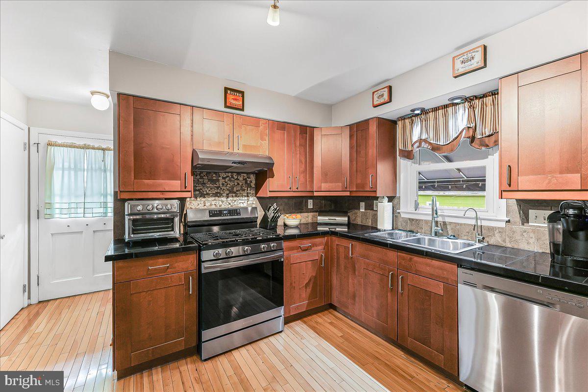 208 Rambling Way Springfield, PA 19064 - Photo 10 of 39 a kitchen with stainless steel appliances a stove sink and cabinets