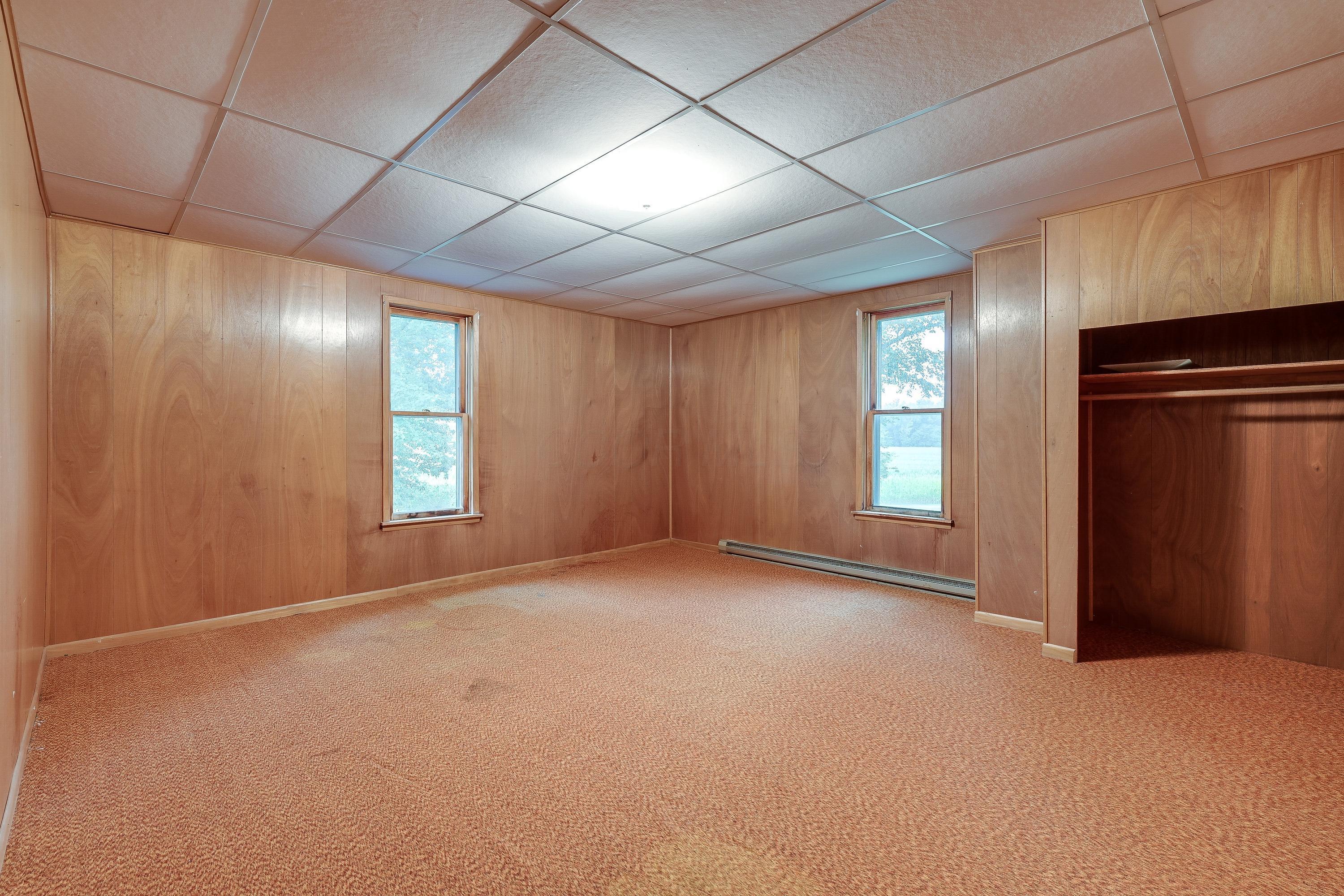 19834 Botkins Road Jackson Center, OH 45334 - Photo 15 of 32 Spacious room featuring wood paneling, drop ceiling, two windows, wall-to-wall carpeting, and an open closet with built-in shelving and hanging rod