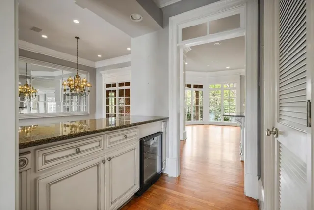 a hall with kitchen island white cabinets and wooden floor