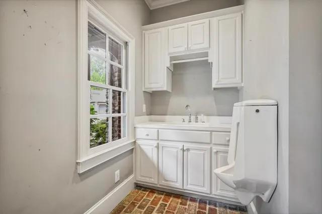 a kitchen with white cabinets and window