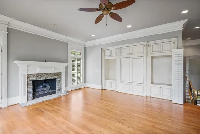 a view of an empty room with wooden floor fireplace and a window