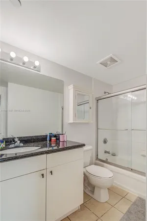 a bathroom with a granite countertop sink a toilet a mirror and shower