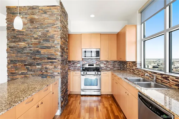 a kitchen with stainless steel appliances granite countertop a sink stove and refrigerator