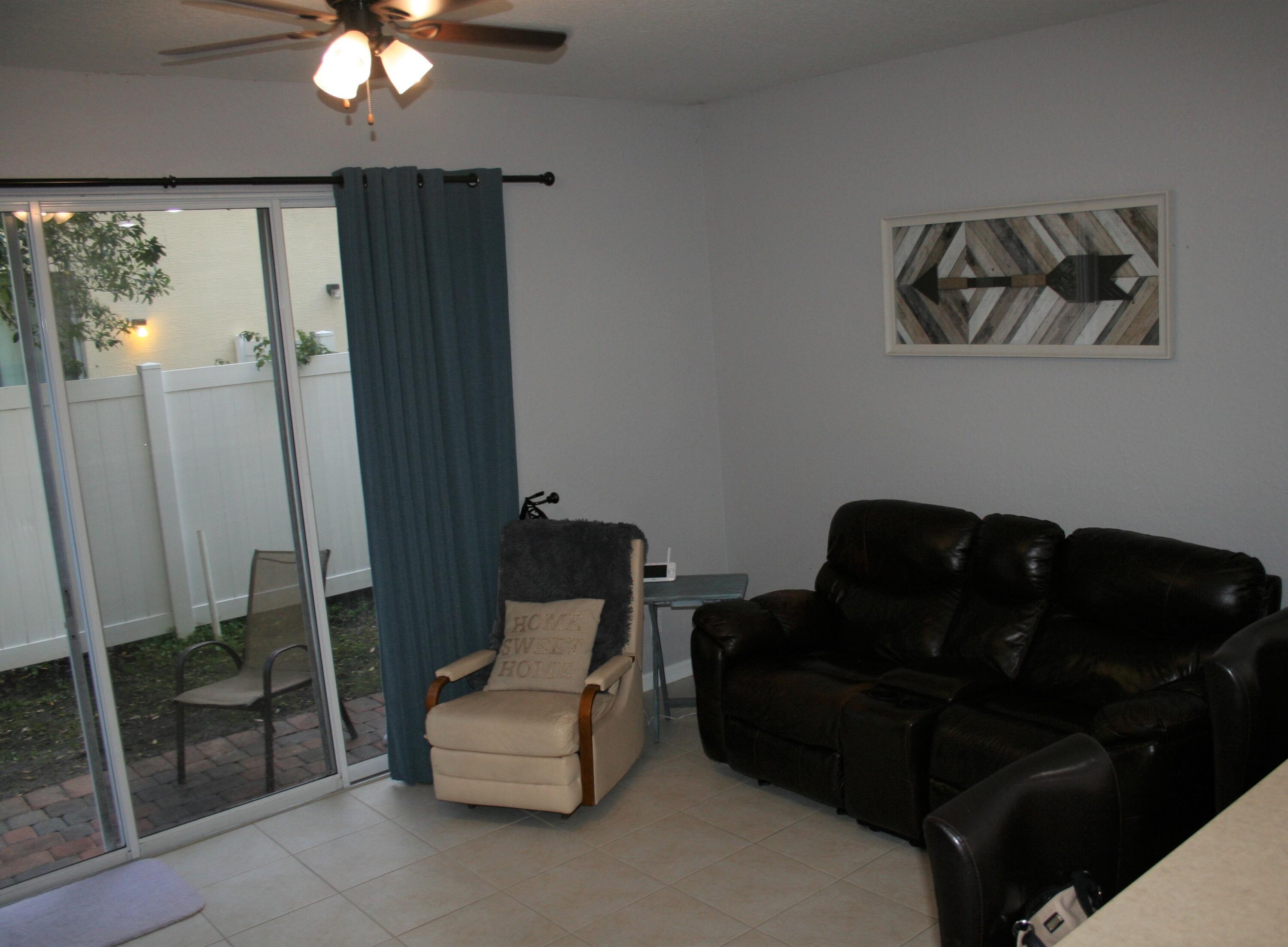 9469 Southwest Purple Martin Way Stuart, FL 34997 - Photo 9 of 23 a living room with furniture and a floor to ceiling window