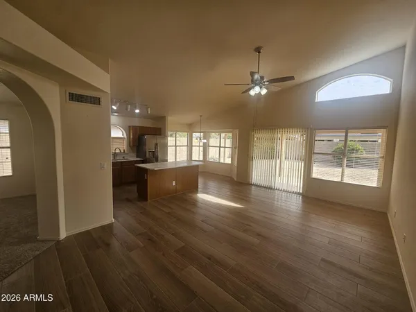 a view of a big room with wooden floor a chandelier fan and windows