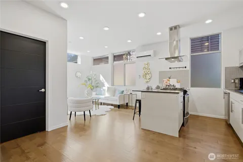 a room with stainless steel appliances kitchen island granite countertop a refrigerator a stove and a dining table with wooden floor