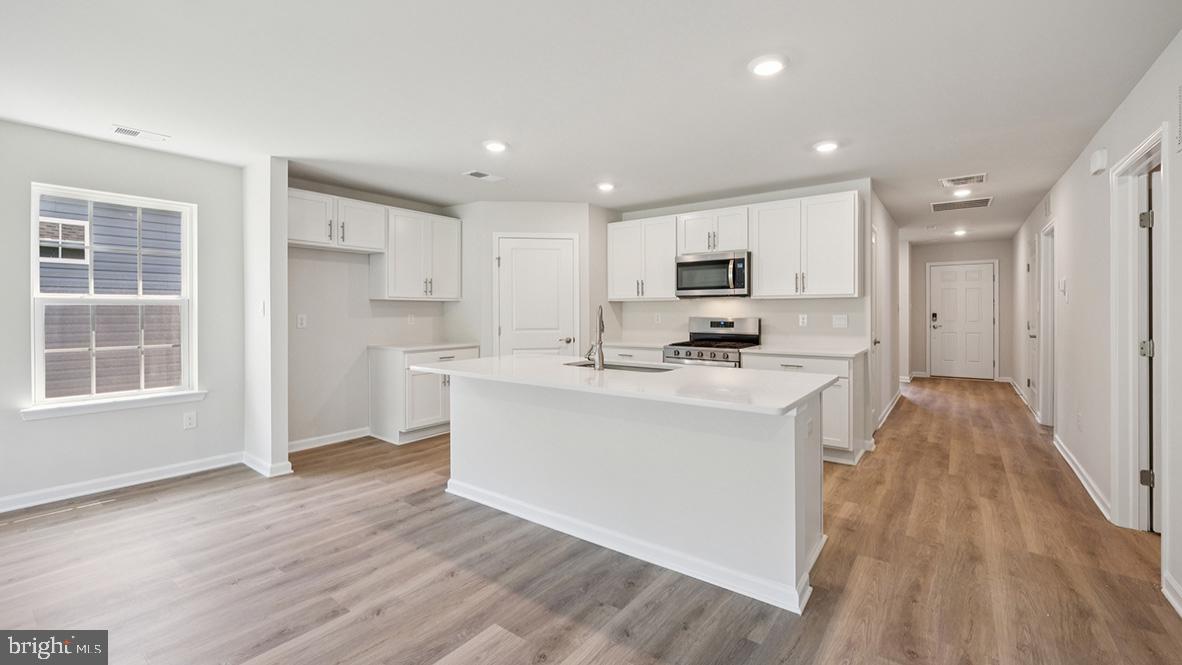 311 Vero Road Egg Harbor Township, NJ 08234 - Photo 12 of 27 a kitchen with stainless steel appliances kitchen island wooden floors and white cabinets
