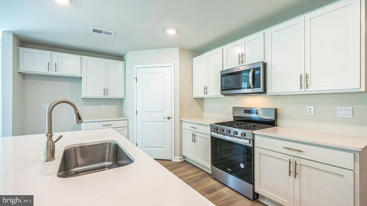 311 Vero Road Egg Harbor Township, NJ 08234 - Photo 19 of 27 a kitchen with white cabinets a sink a stove and a microwave oven with cabinets