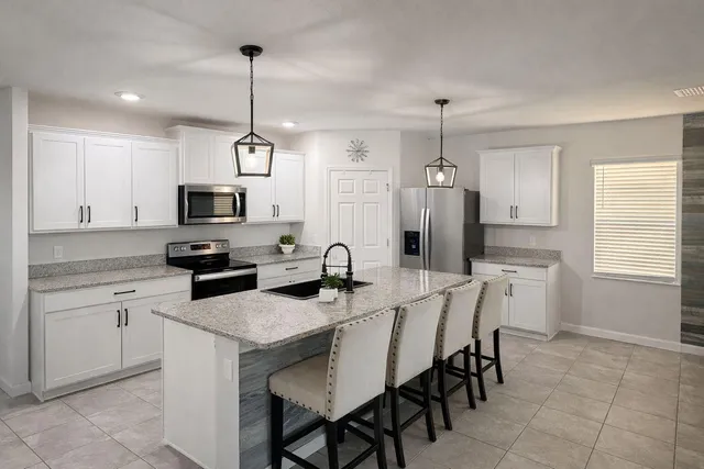 a kitchen that has a table chairs appliances and cabinets