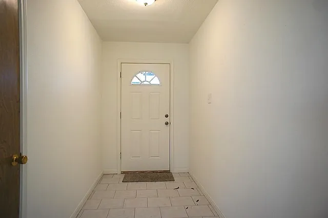 a view of an empty room with window and chandelier fan
