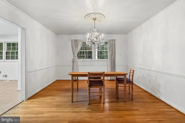 a dining room with wooden floor a chandelier a wooden table and chairs