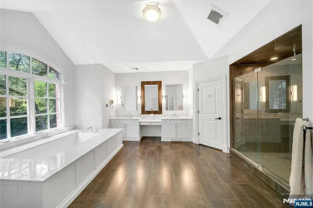a large white bathroom with a double vanity sink large mirror and a bathtub