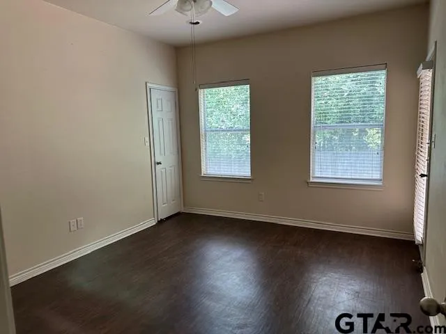 an empty room with wooden floor cabinet and windows