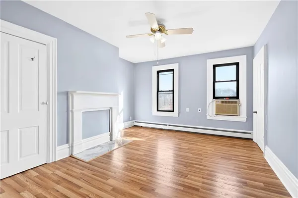 a view of an empty room with window and wooden floor