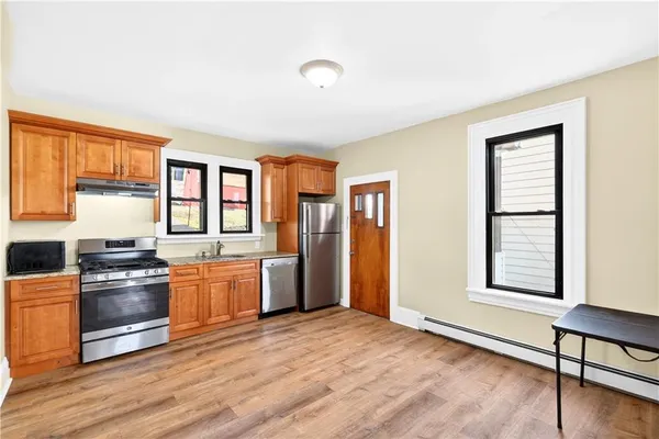 a kitchen with stainless steel appliances granite countertop a stove a sink and a refrigerator with wooden floors