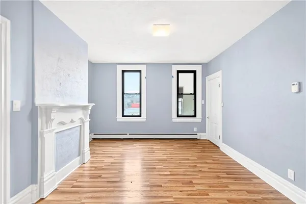 a view of an empty room with window and wooden floor