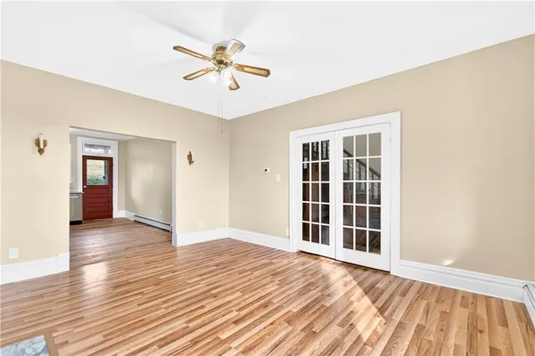 a view of an empty room with wooden floor and a window