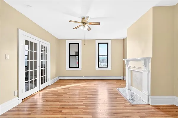 a view of empty room with wooden floor and fan