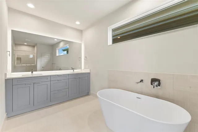 a spacious bathroom with a tub sink and mirror