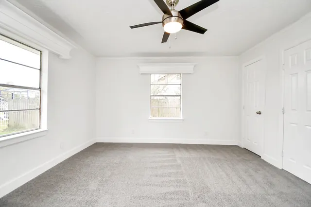 an empty room with a window and a fan
