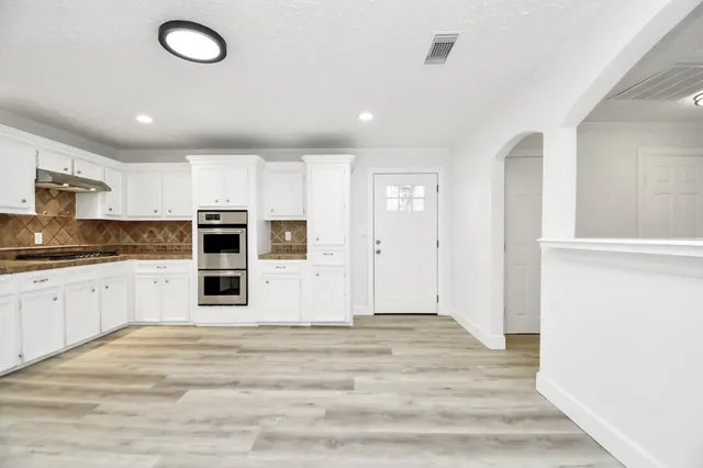 a large white kitchen with kitchen island a sink stainless steel appliances and cabinets