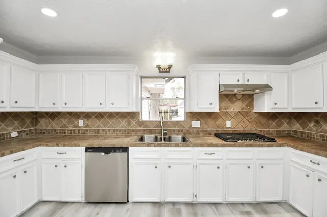 a kitchen with granite countertop white cabinets white appliances and sink