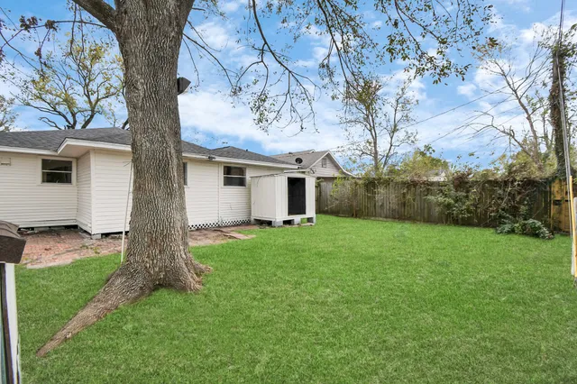 a view of a yard in front of a house with large tree