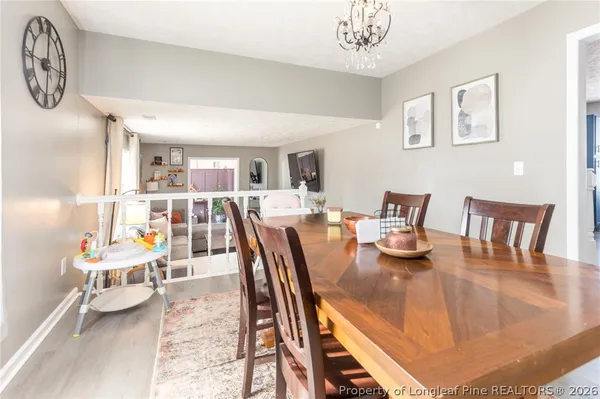 a kitchen with stainless steel appliances a stove a sink a oven a dining table and chairs with wooden floor
