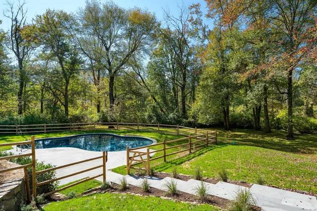 a view of a swimming pool with a bench and trees around