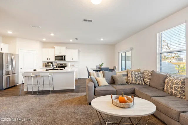 a living room kitchen with white couches and kitchen view