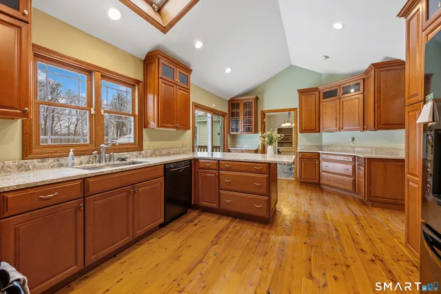 a large kitchen with stainless steel appliances granite countertop a sink dishwasher stove and wooden cabinets