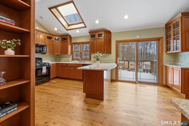 a large kitchen with stainless steel appliances granite countertop a large stove top oven a dining table and chairs with wooden floor