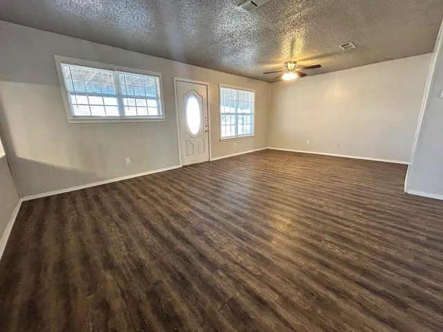 an empty room with wooden floor and windows