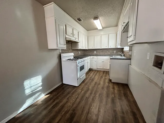 a kitchen with cabinets wooden floor and stainless steel appliances