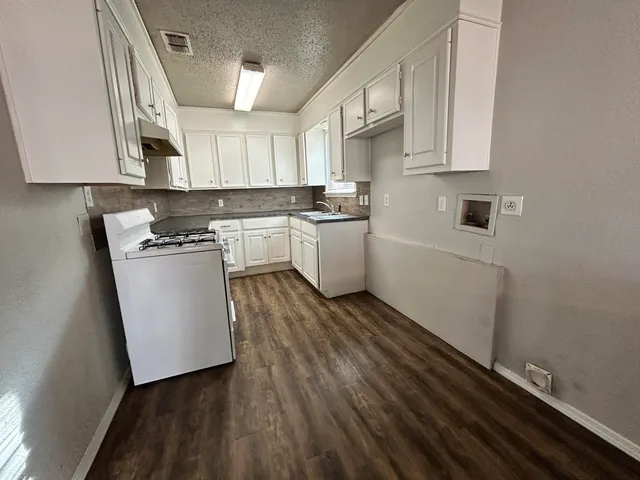 a kitchen with cabinets and wooden floor