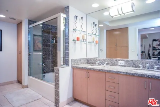 a bathroom with a granite countertop sink a mirror a bathtub and shower