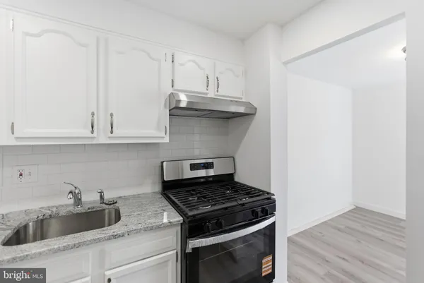 a kitchen with granite countertop white cabinets and stainless steel appliances
