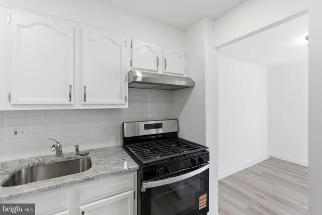a kitchen with granite countertop white cabinets and stainless steel appliances