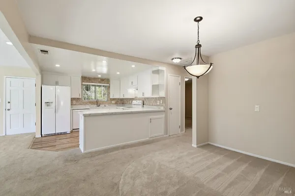 a large white kitchen with a refrigerator a sink and cabinets
