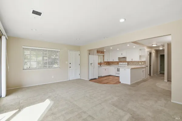 a view of large kitchen with granite countertop cabinets and refrigerator