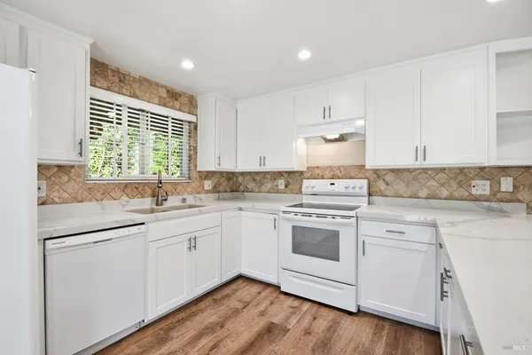 a kitchen with granite countertop white cabinets and white appliances