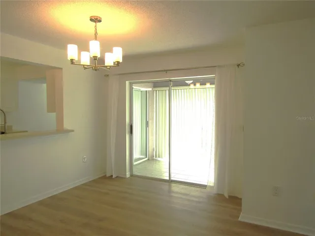 a view of an empty room with wooden floor and chandelier