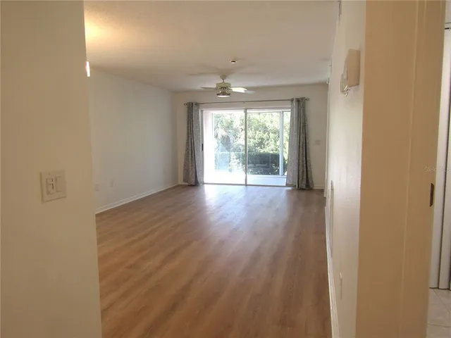 a view of an empty room with wooden floor and a window
