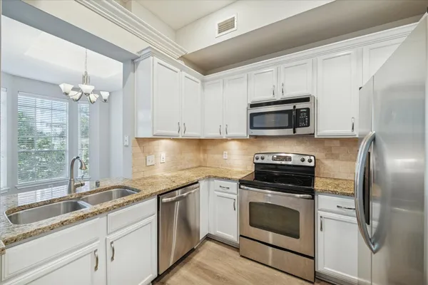 a kitchen with granite countertop a sink stainless steel appliances and cabinets