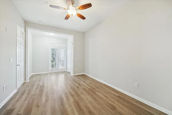 a view of an empty room with wooden floor and a window
