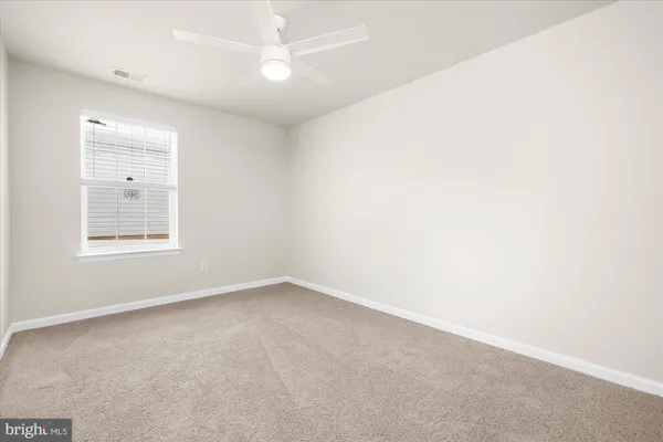 an empty room with a window and ceiling fan